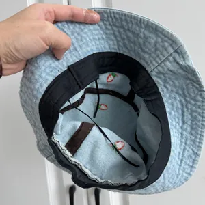 Interior view of light blue denim bucket hat showing red strawberry embroidery detail
