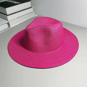 Close-up of a pink woven Panama straw hat with a wide brim and jazz fedora shape