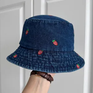 Detailed view of a dark blue denim bucket hat featuring cute red strawberry embroidery