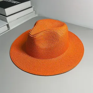 Macro view of a vibrant orange woven Panama straw hat placed on a neutral desktop