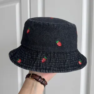Detailed view of the black denim bucket hat featuring vibrant red strawberry embroidery