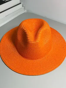 Detail view of a vibrant orange woven Panama straw hat for stylish summer sun protection.