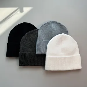 Detailansicht von vier weichen Strickmützen in neutralen Farben für kalte Wintertage