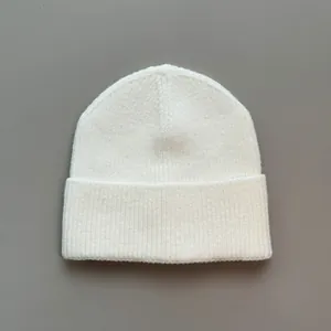 Detailansicht der weichen weißen Strickstruktur einer winterlichen Beanie-Mütze