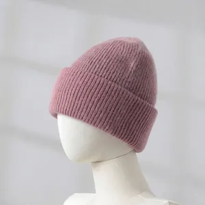 Detail of warm pink knit beanie hat on a mannequin head, soft winter accessory