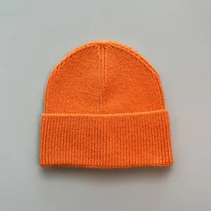 Detailansicht der leuchtend orangen Strickmütze mit weicher Textur und geripptem Umschlag.