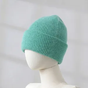 Close-up detail of a soft mint green rabbit fur knitted beanie showing ribbed texture