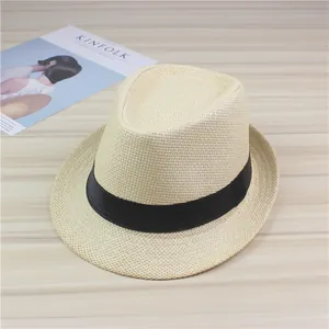 Detailed view of a cream straw fedora hat with a black ribbon band on wood surface