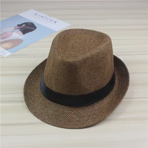 Detailed view of a brown woven straw fedora hat with a black band on a wooden table
