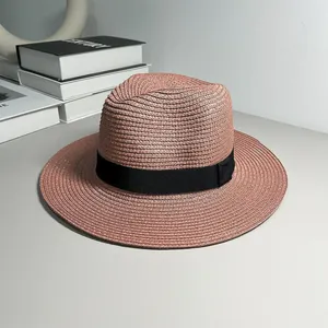 Close-up detail of a pink straw Panama hat with a black ribbon band and woven texture