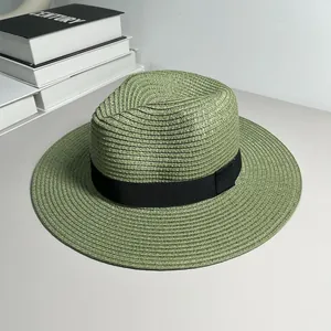 Detailed view of a woven green straw Panama fedora hat with a black ribbon band