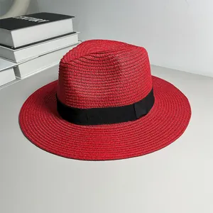 Close-up of red Panama straw hat with a classic black ribbon band and woven texture