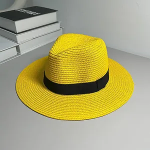 Close-up detail of a bright yellow Panama straw hat with a classic black ribbon band.