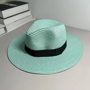 Close-up detail of mint green Panama straw hat featuring elegant black ribbon band.