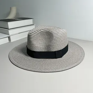 Classic grey straw Panama fedora hat with black ribbon detail on a minimalist desk