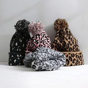 Group of four stylish leopard print knit beanies with fluffy pom-poms for winter warmth