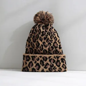 Detailed view of stylish leopard print knit beanie featuring a fluffy pom-pom and soft texture