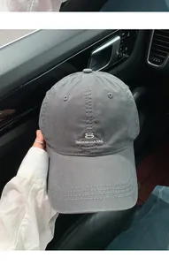 Dettaglio cappellino da baseball grigio con ricamo minimalista all'interno dell'auto