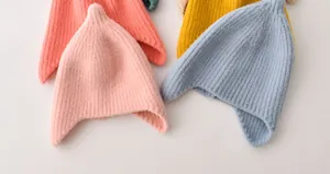 Groep kleurrijke puntige babygebreide mutsen met oorkleppen in zachte snoepkleuren.