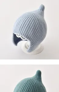 Detail van zachte geribbelde baby elfenmuts met oorkleppen in blauwe en groenblauwe kleuren