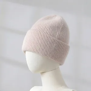 Close-up detail of a soft pink rabbit hair knitted beanie on a white mannequin head display