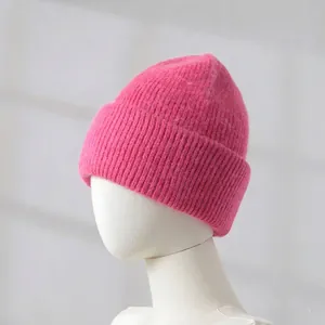 Close-up detail of a soft pink rabbit hair knitted beanie displayed on a mannequin