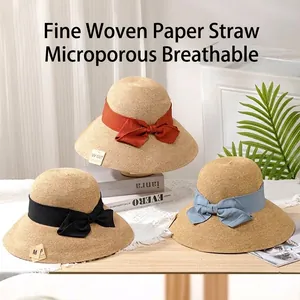 Detailed view of three stylish woven paper straw sun hats featuring colorful bow ribbons
