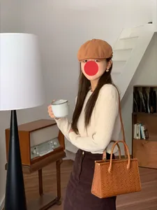 Modella asiatica con berretto vintage marrone in un interno caldo dallo stile rétro