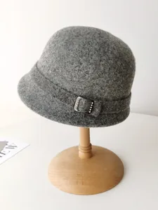 Detail view of an elegant gray wool cloche hat with decorative buckle on a wooden stand