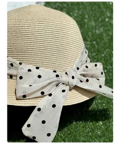 Dettaglio di un elegante cappello di paglia con fiocco a pois sull'erba verde
