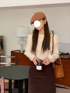 Dettaglio di una coppola retrò stile britannico color caramello su modella in interno.