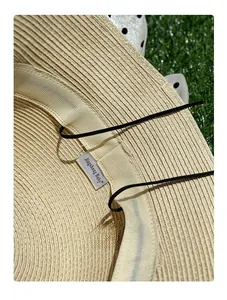Dettaglio dell'interno di un cappello di paglia intrecciato con cinturino e marca.