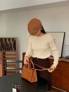 Primo piano di una donna che indossa un berretto newsboy marrone vintage in interni.