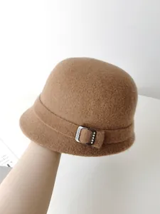 Close-up detail of an elegant camel brown wool felt cloche hat with a decorative rhinestone buckle