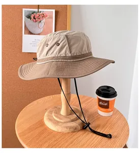 Detail of a khaki sun hat on a wooden stand next to a coffee cup