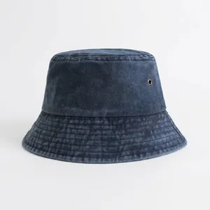 Vista dettagliata della trama in denim lavato e dell'occhiello in ottone su un cappello a secchiello