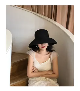 Elegant French vintage black large brim straw sun hat shown on a model in a stylish indoor setting
