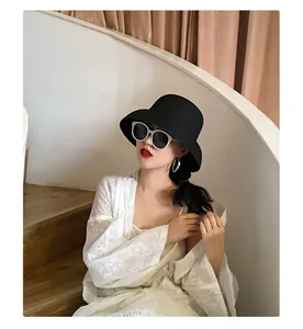 Stylish Asian woman wearing a black wide-brimmed straw hat and white lace robe.