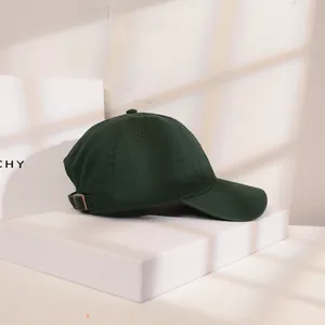 Detailansicht einer dunkelgrünen Baumwoll-Baseballkappe vor einer minimalistischen Wand