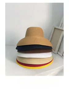 Detail view showing a stack of multi-colored wide brim straw sun hats in a minimal setting
