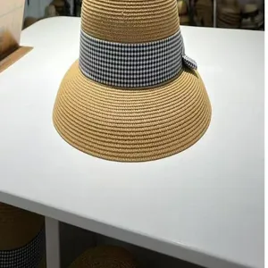 Detailaufnahme eines beigen Strohhuts mit schwarz-weißem Karoband für den Sommerurlaub.