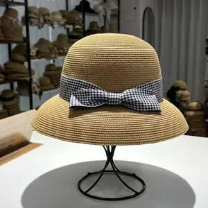 Strohhut für den Sommer mit schwarz-weißer Gingham-Schleife für Strand und Reisen.