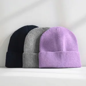 Detailed macro view showing the soft texture of navy, grey and purple knit beanies.