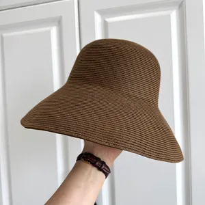 Detailed side view of a brown woven straw sun hat with a wide brim for beach sun protection.