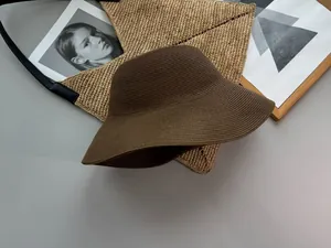 Detailed view of a brown foldable Japanese style straw bucket hat on a minimalist grey background