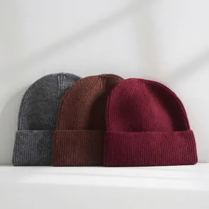 Detailed view of three warm knitted beanies in gray, brown, and burgundy solid colors.