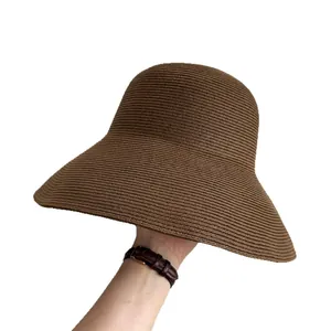 Stylish brown wide-brim straw sun hat for women being held against a white background