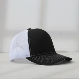 Detailed profile view of a black and white mesh trucker hat with contrast stitching details.