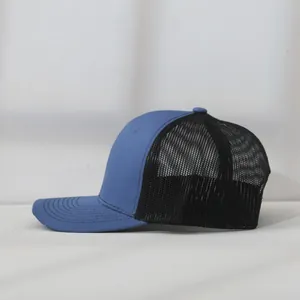Side view detail of a blue and black mesh trucker baseball cap with curved brim.