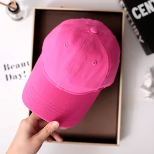 Nahaufnahme einer leuchtend rosa Baumwoll-Baseballkappe, die in der Hand gehalten wird.